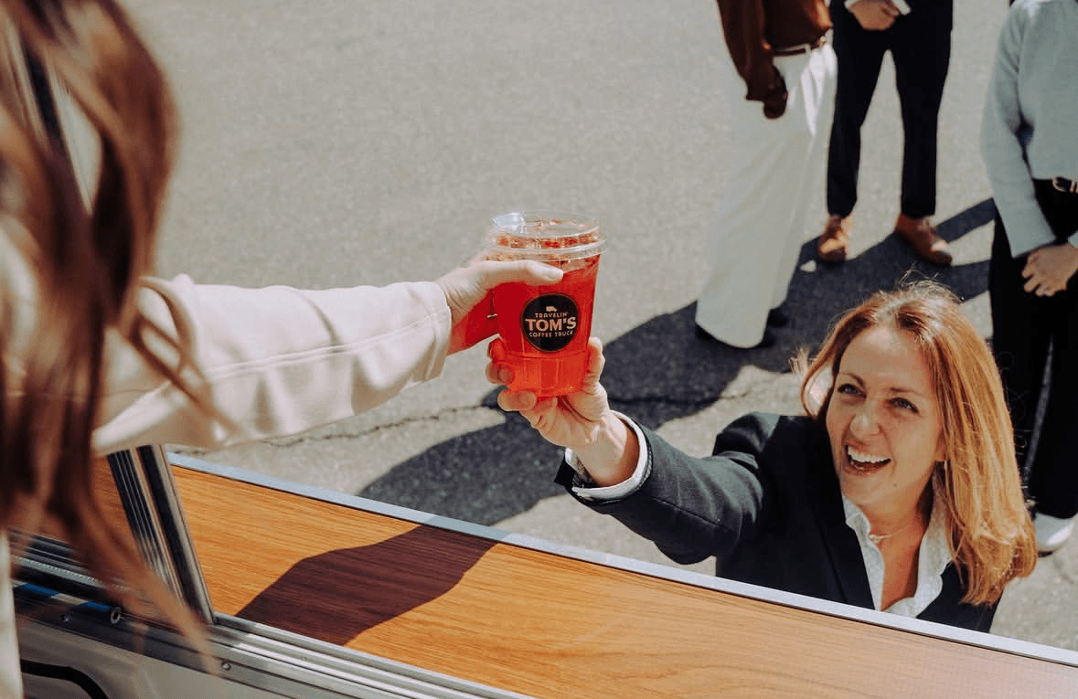 A barista hands a Travelin' Tom's coffee through the truck window